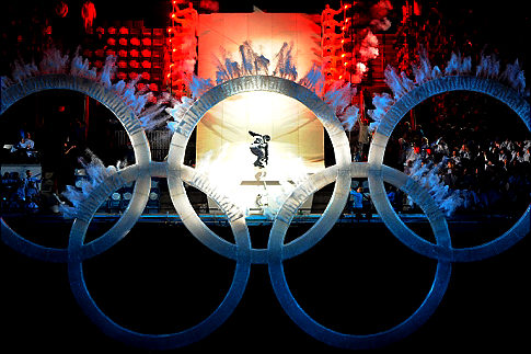 Snowboarder jumping through Olympic rings