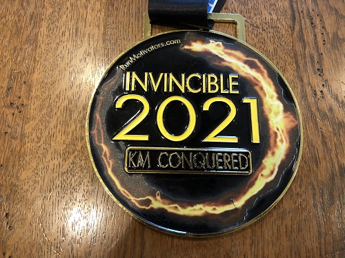 Medal that says 'Invincible 2021 KM Conquered'